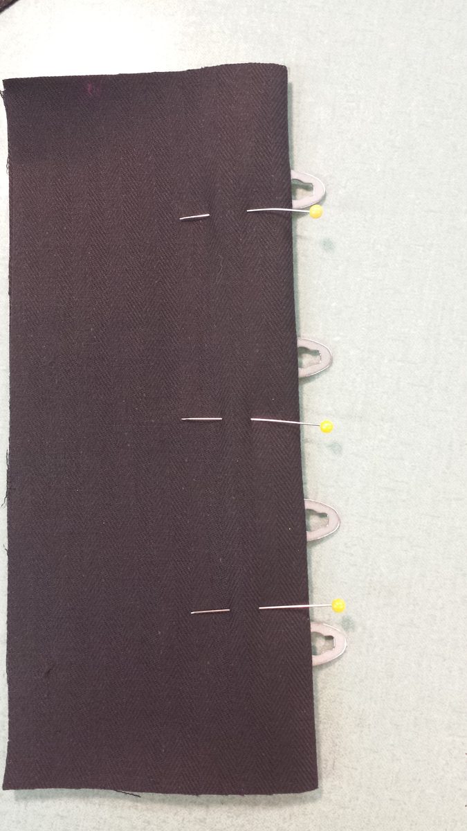 Eye side of the busk pinned in place between the face fabric and lining